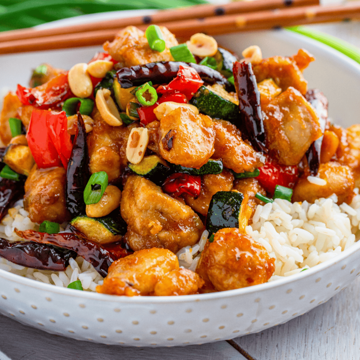 Air fryer crispy Kung Pao chicken with peanuts and vegetables on a plate.