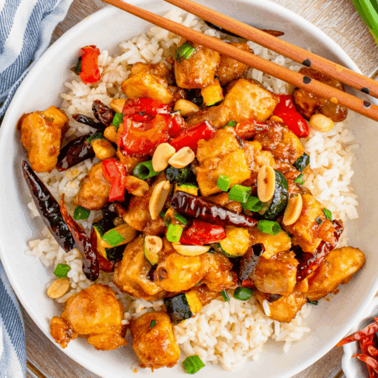 Copycat Panda Express Kung Pao Chicken served with peppers and peanuts on a white plate.