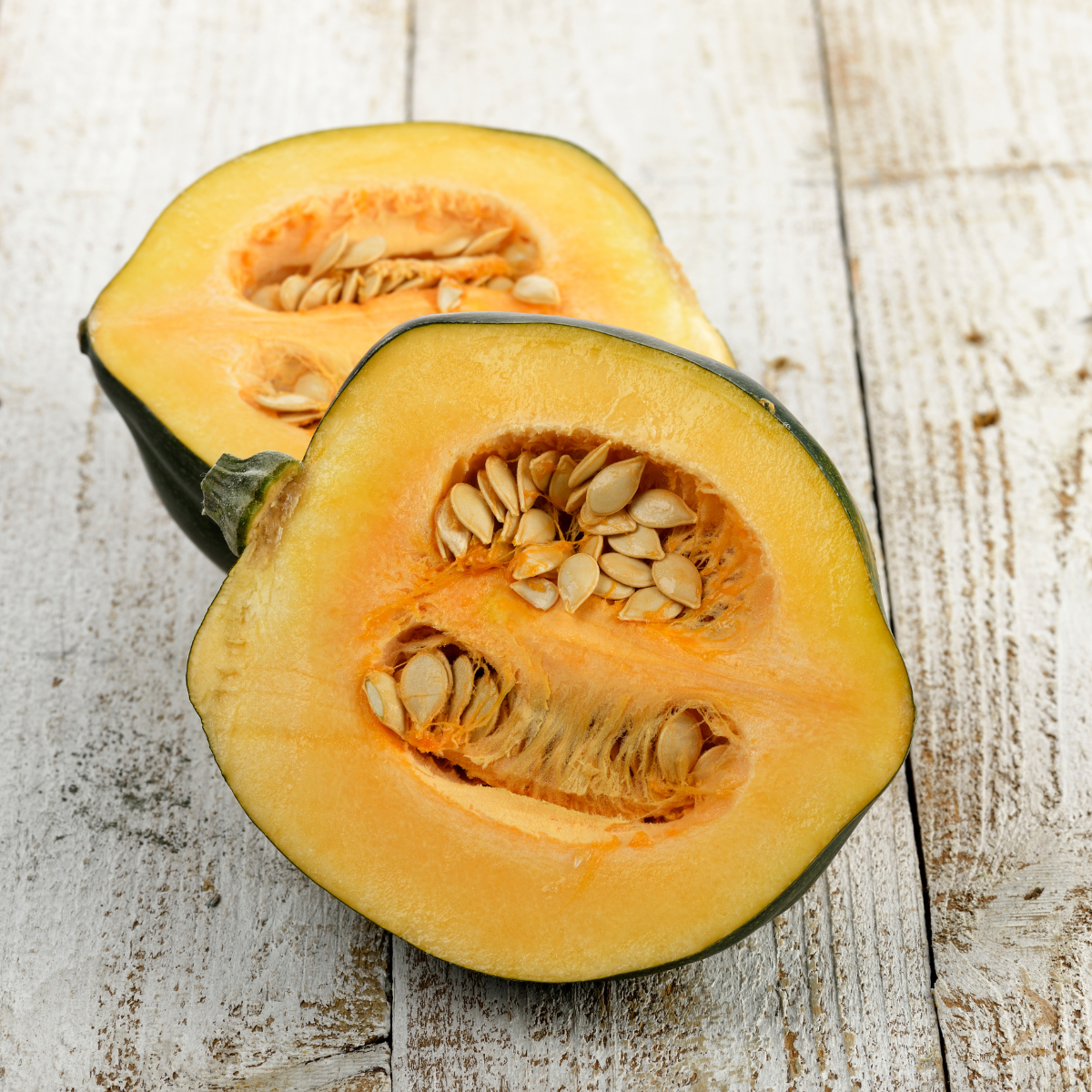 Picture of acorn squash cut in half, on wooden table.