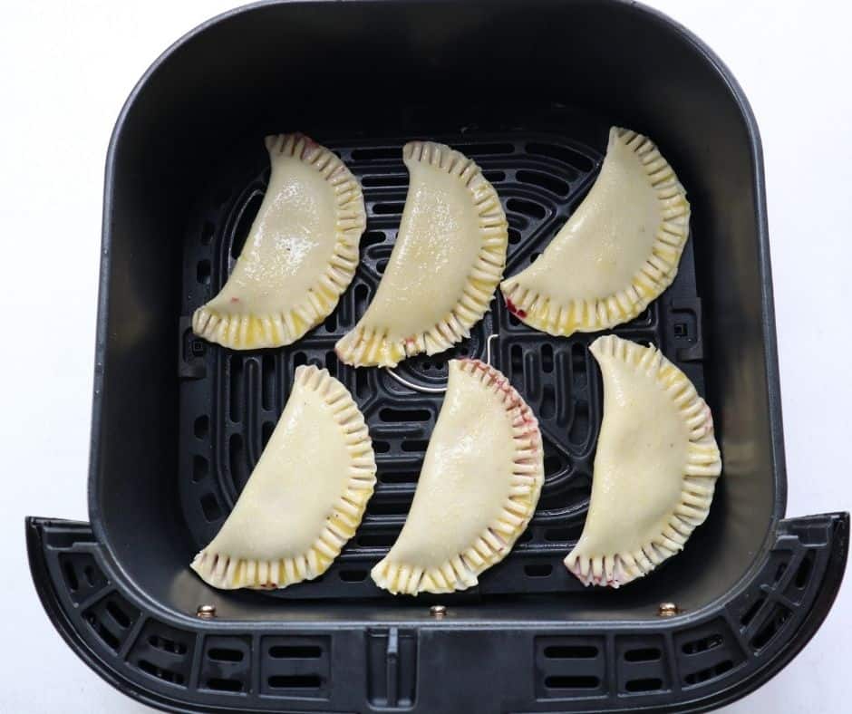 "Arranging hand pies in the air fryer basket for cooking"