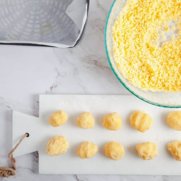 Scooping Kourabiedes cookie dough onto a sprayed or parchment-lined air fryer tray using an ice cream scoop
