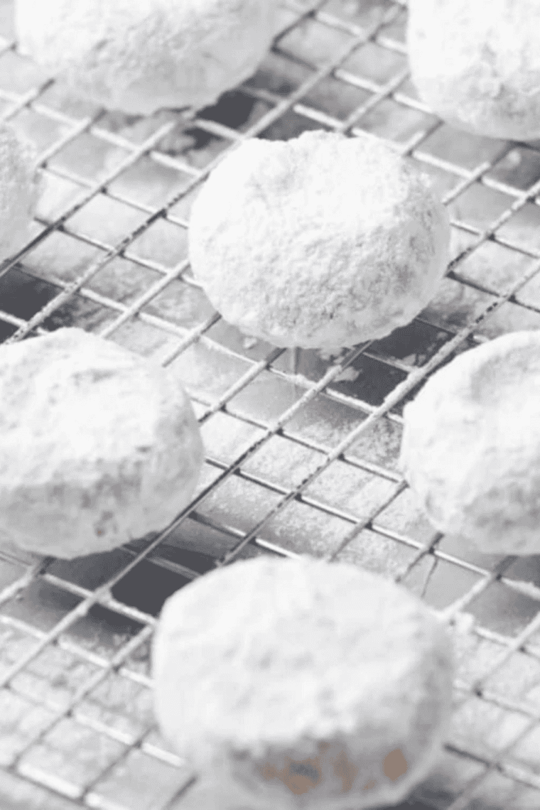 Air Fryer Greek Kourabiedes cookies shaped as crescents and dusted with powdered sugar on a plate