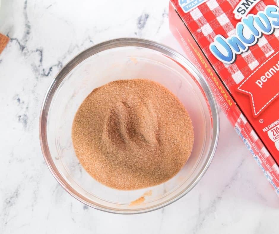 Mixing granulated sugar and ground cinnamon together in a small bowl for donut coating