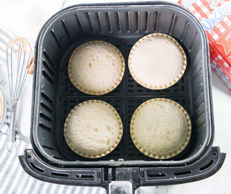Placing Uncrustables in an air fryer basket sprayed with cooking spray, cooking at 350°F and flipping halfway through