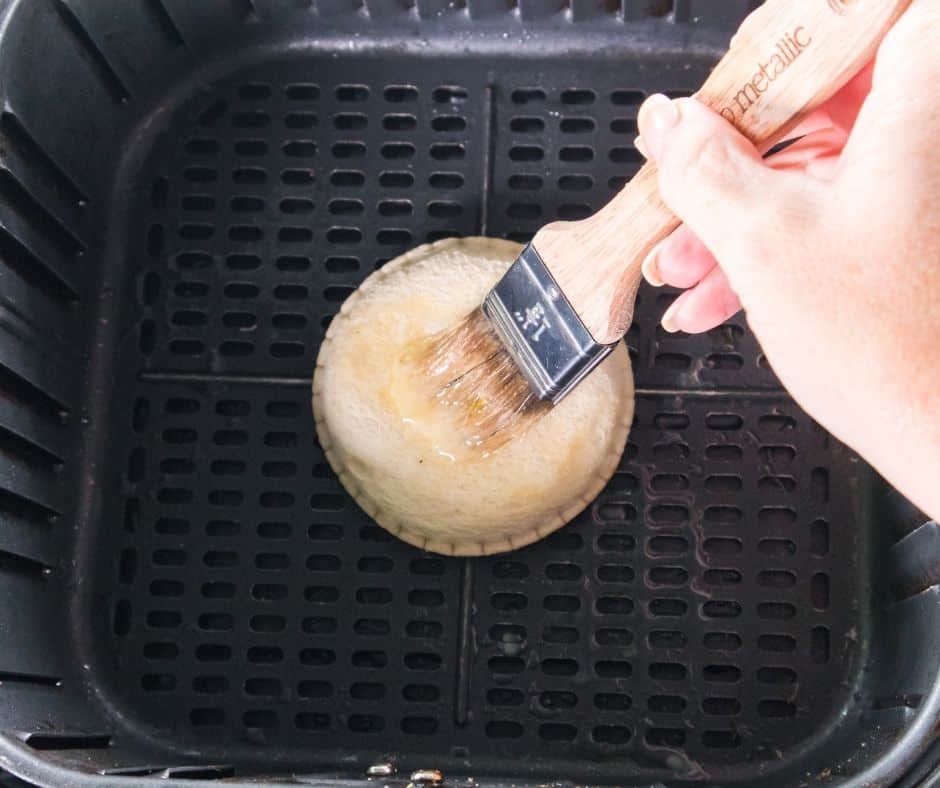 Brushing air-fried Uncrustable donuts with melted butter and coating them in cinnamon sugar mixture
