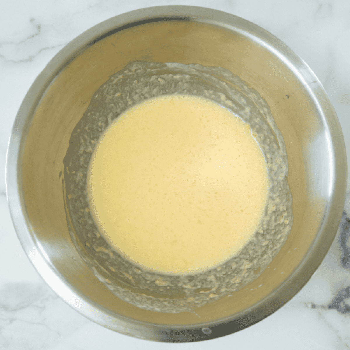 Mixing buttermilk, melted butter, eggs, and salt together in a large metal bowl.