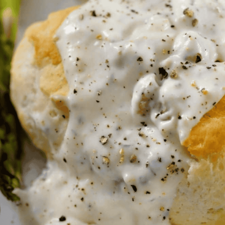 Rich and creamy Cracker Barrel Sawmill Gravy served over biscuits in a rustic bowl