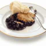 Easy air fryer blueberry cobbler with golden topping and bubbling blueberries in a baking dish.