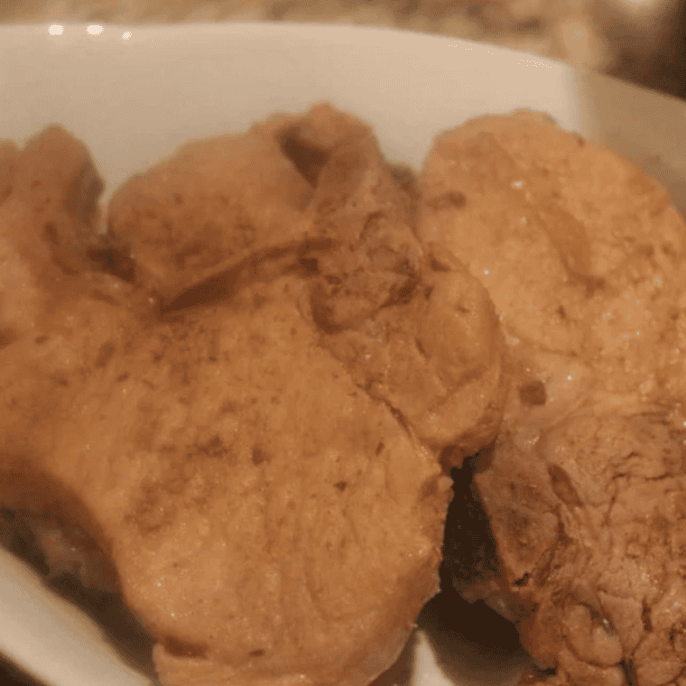 Cooked pork chops on white plate.
