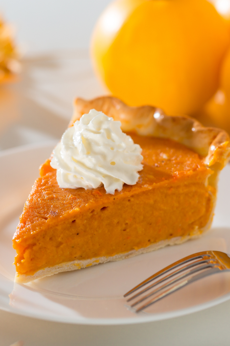 Whole Instant Pot pumpkin pie on a wooden board with a graham cracker crust edge and a piped whipped cream border