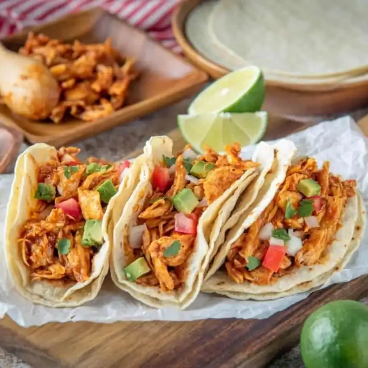 Easy 3-ingredient shredded salsa chicken in a warm tortilla, topped with avocado and cilantro
