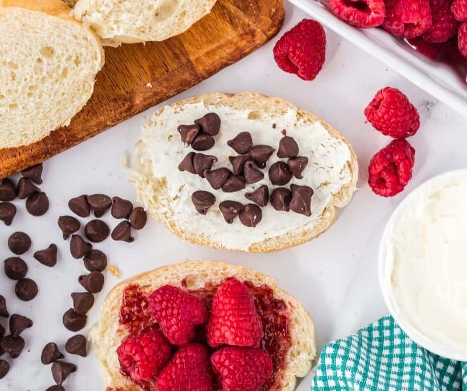Fresh raspberries on one bread slice and chocolate chips on the mascarpone-covered slice, ready to assemble.