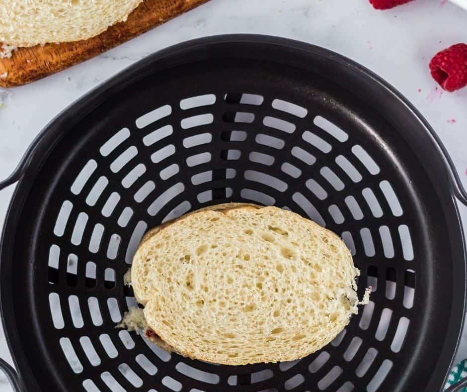 Sandwich buttered on both sides, cooking in the air fryer until golden brown and melty.