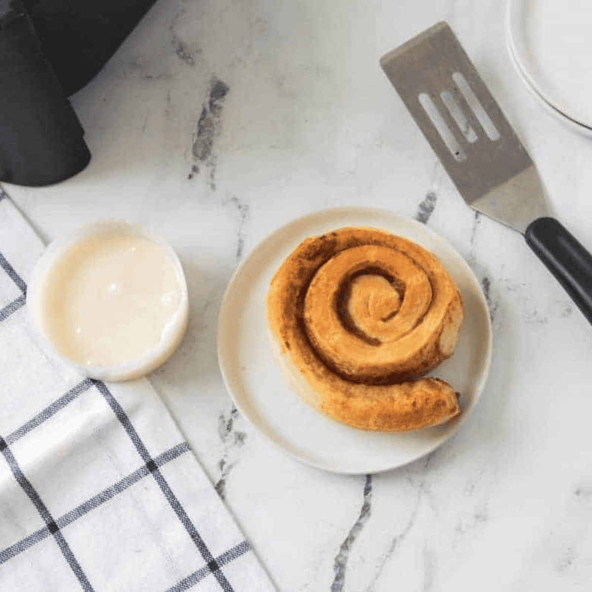 Golden brown Pillsbury cinnamon rolls cooked in the air fryer, drizzled with icing and ready to serve.