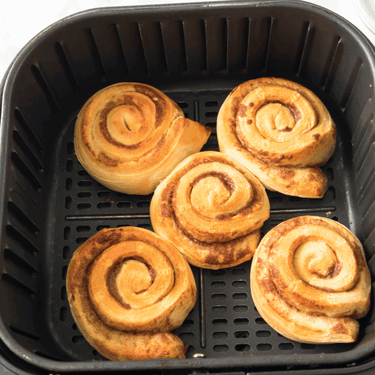 Cooked Pillsbury Cinnamon Rolls in the air fryer basket.