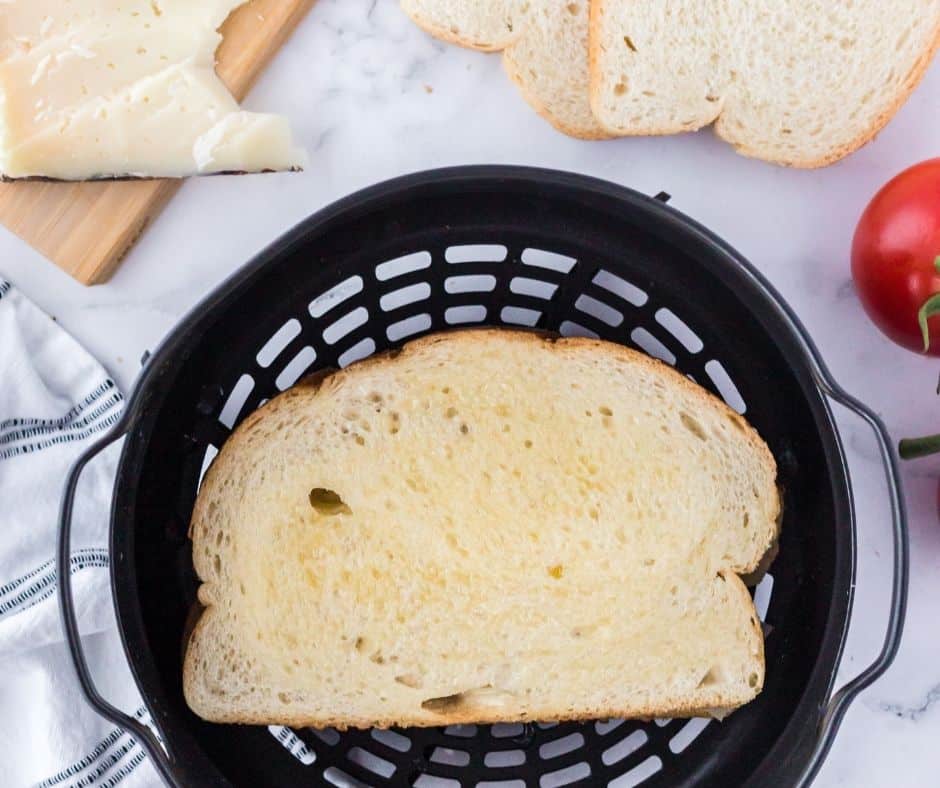 Air fryer cooking a buttered Manchego grilled cheese sandwich until golden brown.