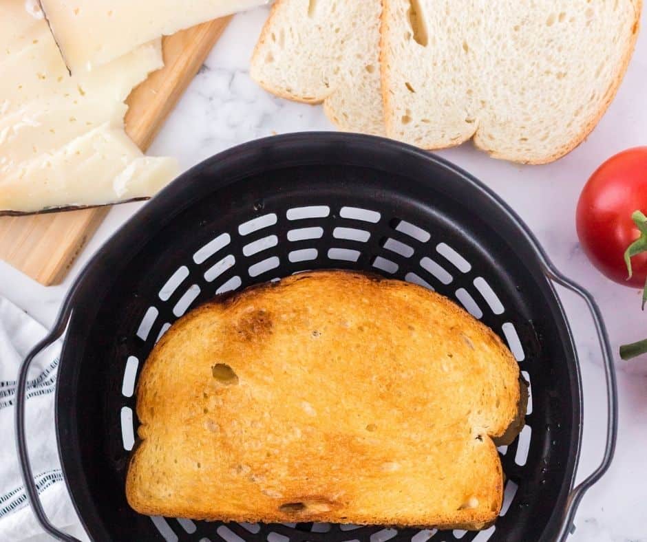 Flipping Manchego grilled cheese in the air fryer for even crispiness.