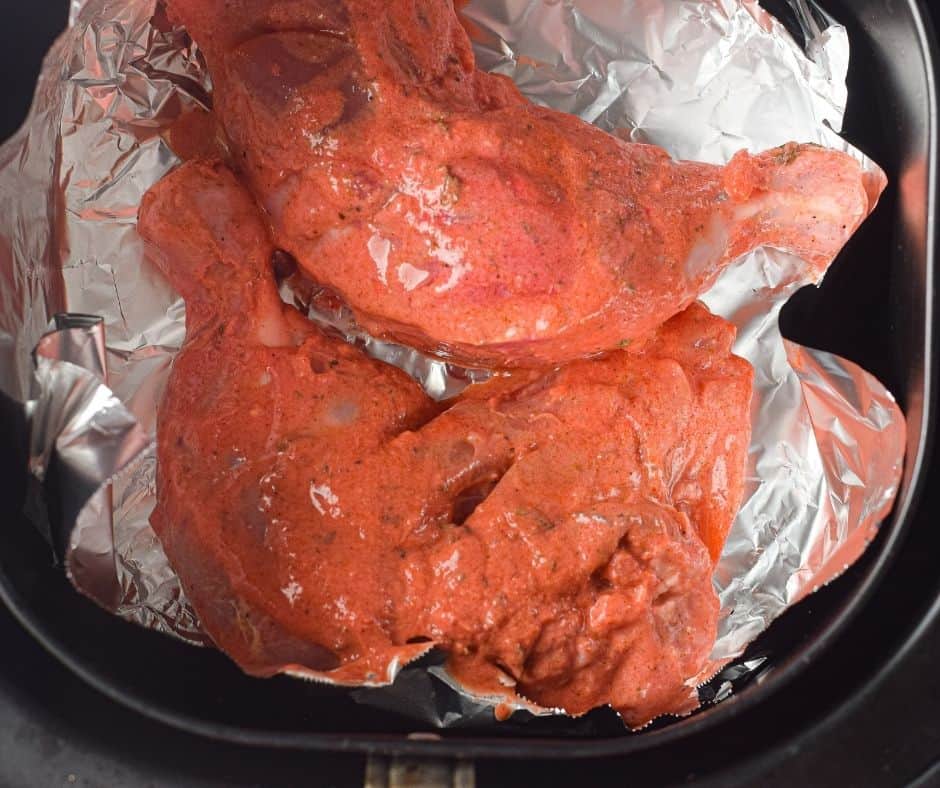 Marinated chicken pieces arranged neatly in the air fryer basket.