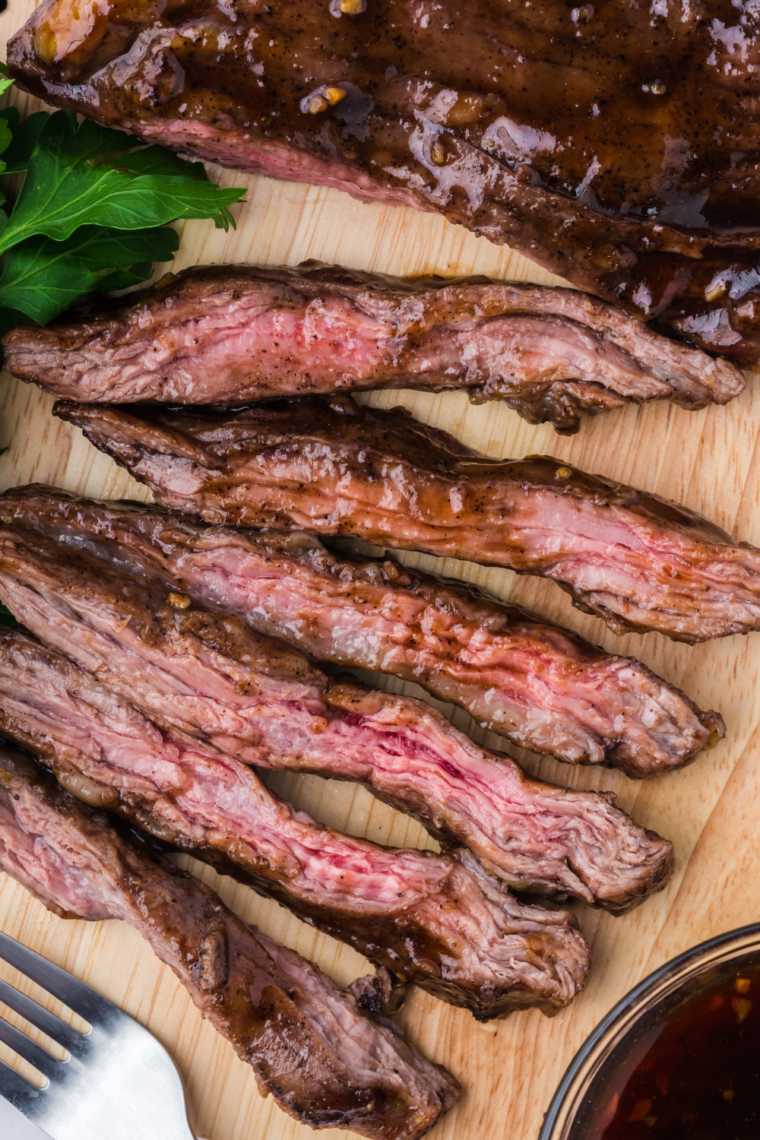Sliced air fryer skirt steak served on a plate with browned crispy edges and herbs garnish