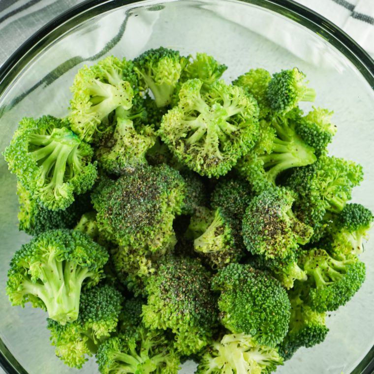 Fresh broccoli florets being patted dry on a kitchen towel before air frying