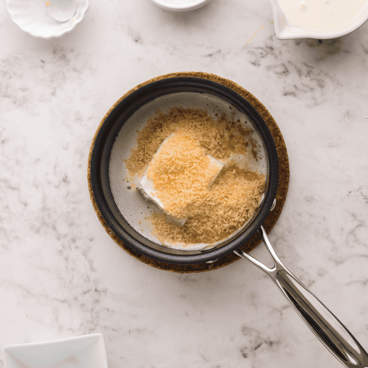 Melting butter in a saucepan and adding heavy whipping cream, cream cheese, Parmesan, and garlic to create a smooth Alfredo sauce.