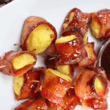 Air Fryer Bacon Wrapped Pineapple bites with crispy bacon and caramelized edges, served on a white plate.