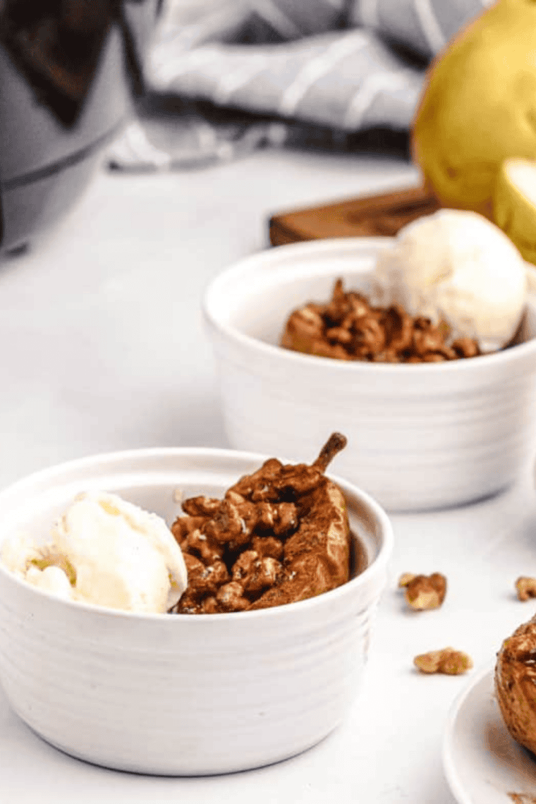Warm air fryer baked pear served in a white ramekin with a cinnamon caramelized topping and honey drizzle.