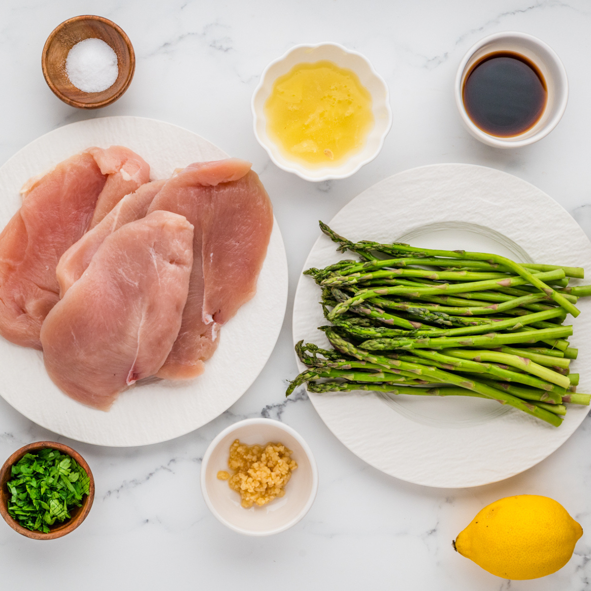 Ingredients needed for chicken and asparagus on plate.