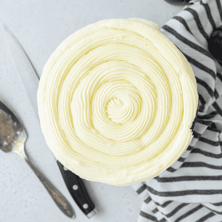 Air Fryer Flourless Chocolate Cake topped with smooth white frosting, served on a white plate with a rich, fudgy chocolate interior.