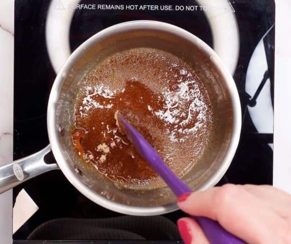 Honey and brown sugar simmering in a small saucepan, stirring until the sugar dissolves.