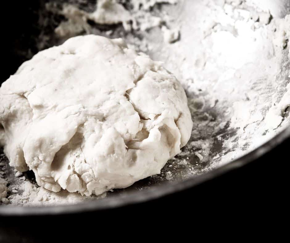 Mixing cold, diced butter with flour, sugar, and salt in a large bowl, adding water until dough forms.