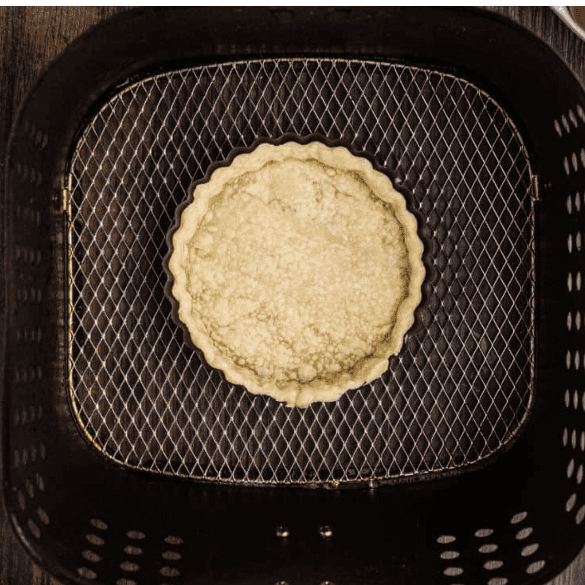 Cooked pie crust in the air fryer basket.