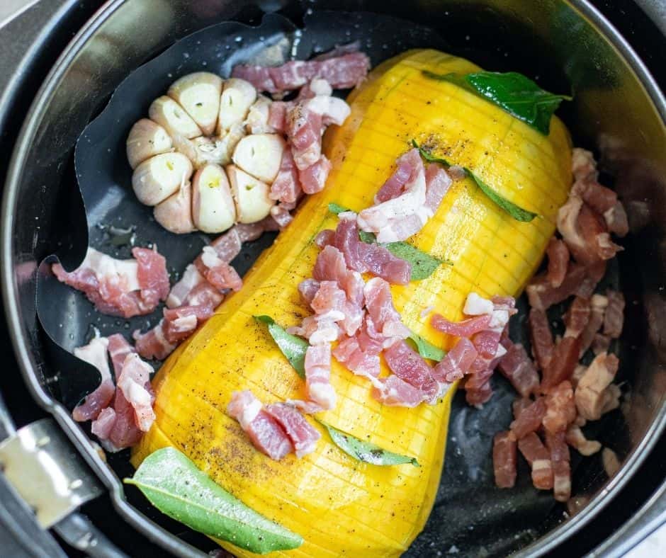 Hasselback Butternut Squash with diced bacon on top, placed in air fryer basket