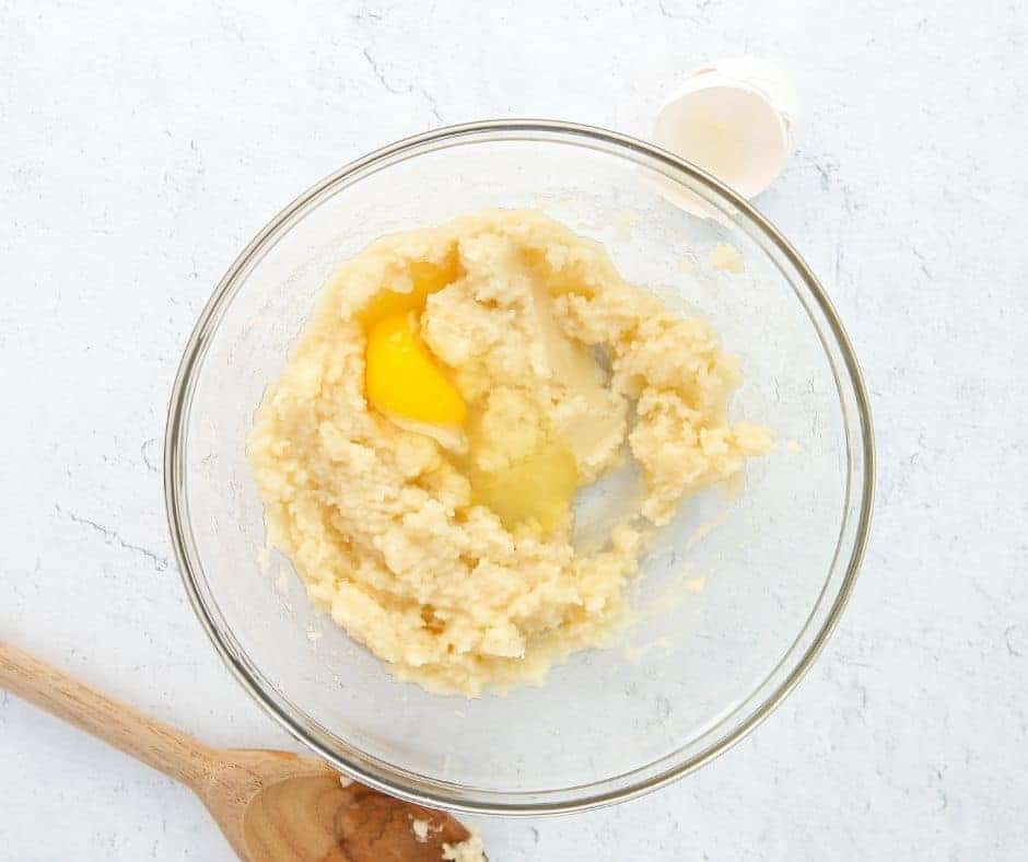 Beat in eggs one at a time until dough forms a stiff, shiny texture.