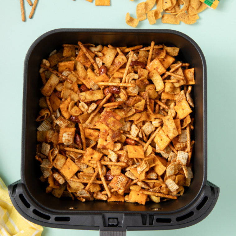 Caramel apple trail mix spread in an even layer in a parchment-lined air fryer basket