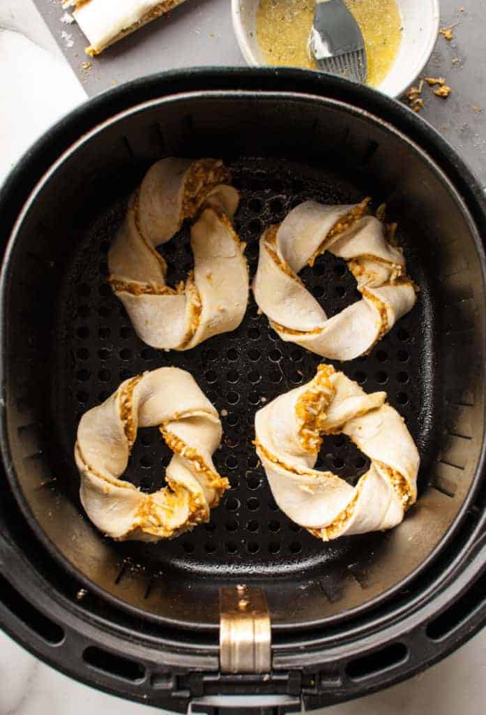 Uncooked savory pumpkin twists arranged in the air fryer basket, ready to be air-fried until golden and crispy.