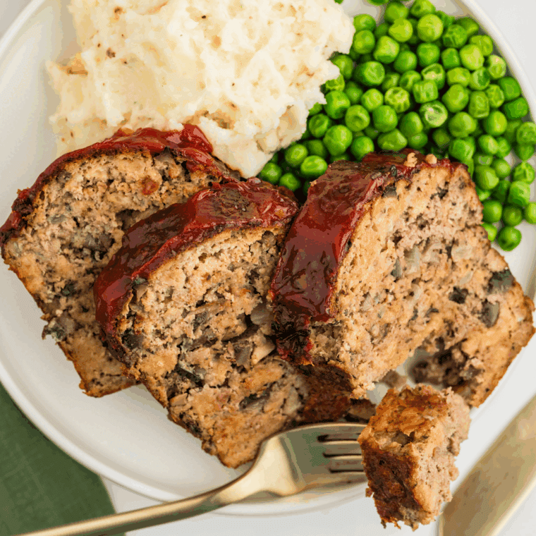 Sliced meatloaf without eggs served with mashed potatoes and green beans.