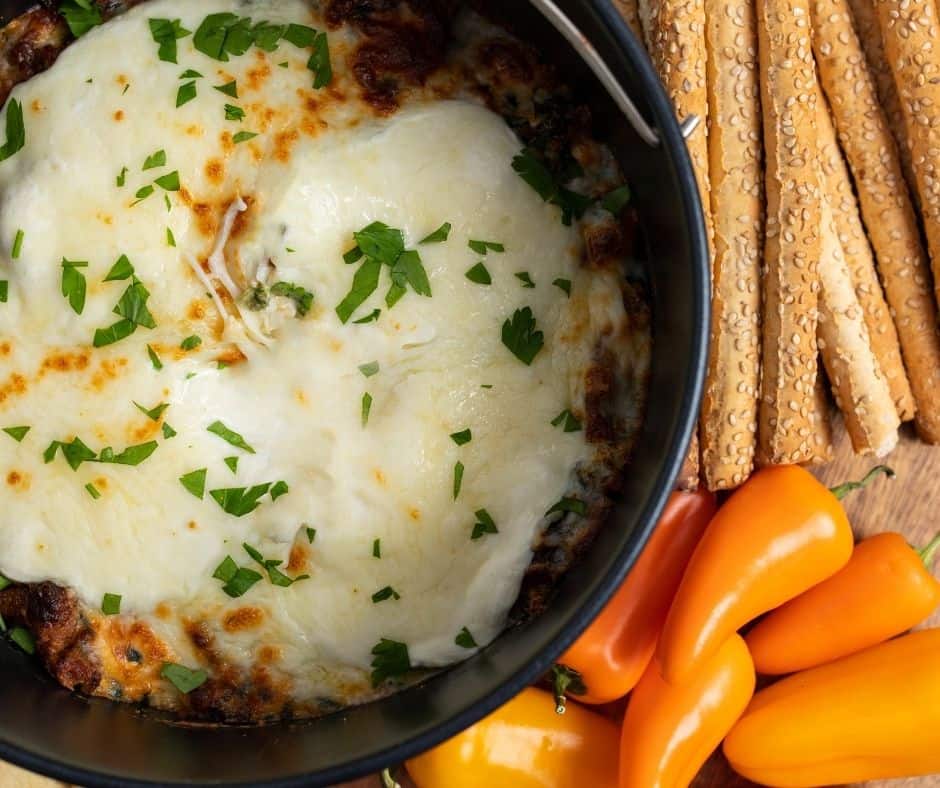 Air Fryer Cheesy Bacon Spinach Dip in a bowl with crispy bacon and melted cheese on top, served with chips for dipping.