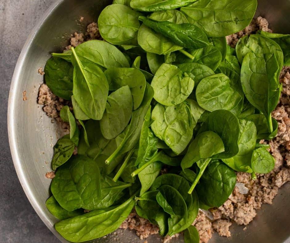 Cook sausage in a large skillet with fennel seeds and red pepper flakes, then add spinach leaves and sauté until wilted.