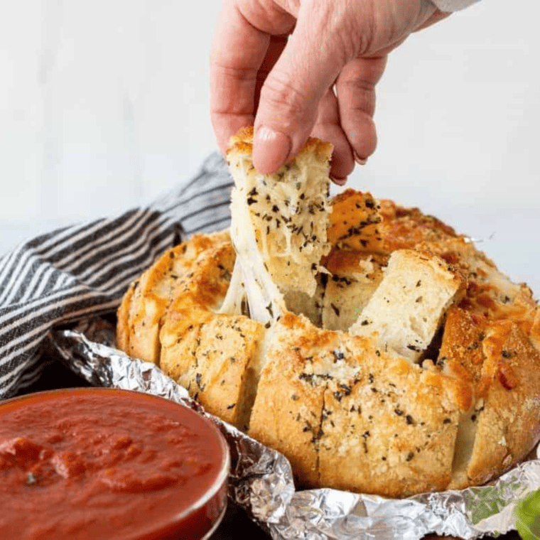 Golden-brown Air Fryer Mozzarella Pizza Bread topped with melted cheese and pizza sauce, served on a wooden board.