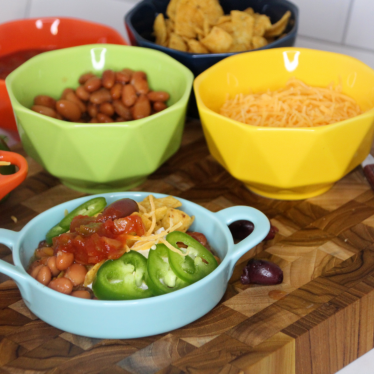 Air Fryer Frito Pie in a casserole dish with layers of Fritos, chili, and melted cheese, garnished with green onions
