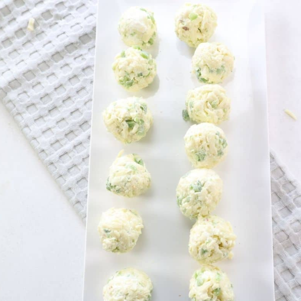 Placing cheese balls on parchment paper to freeze on a baking sheet