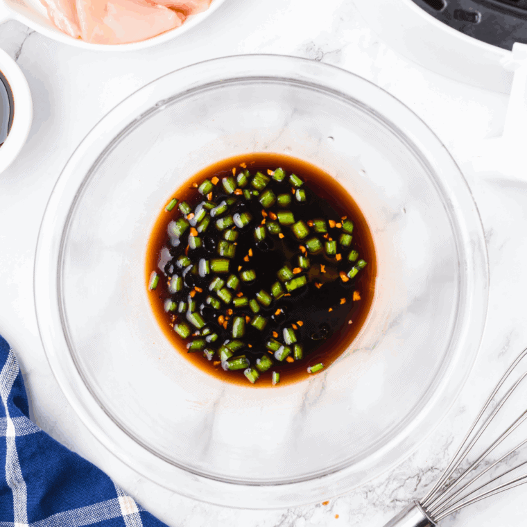 Mixing soy sauce, garlic, ginger, sesame oil, honey, salt, and pepper in a bowl to make chicken marinade.