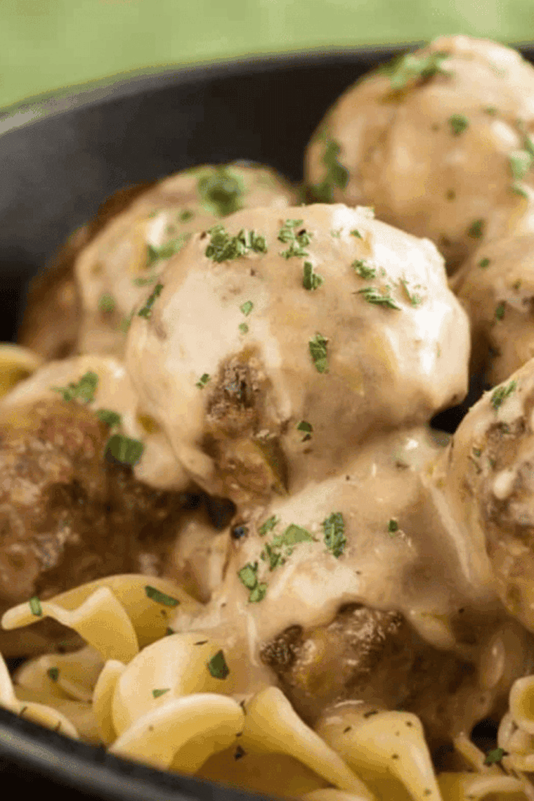 Air fryer Swedish meatballs coated in creamy sauce, served on a plate with fresh garnish.