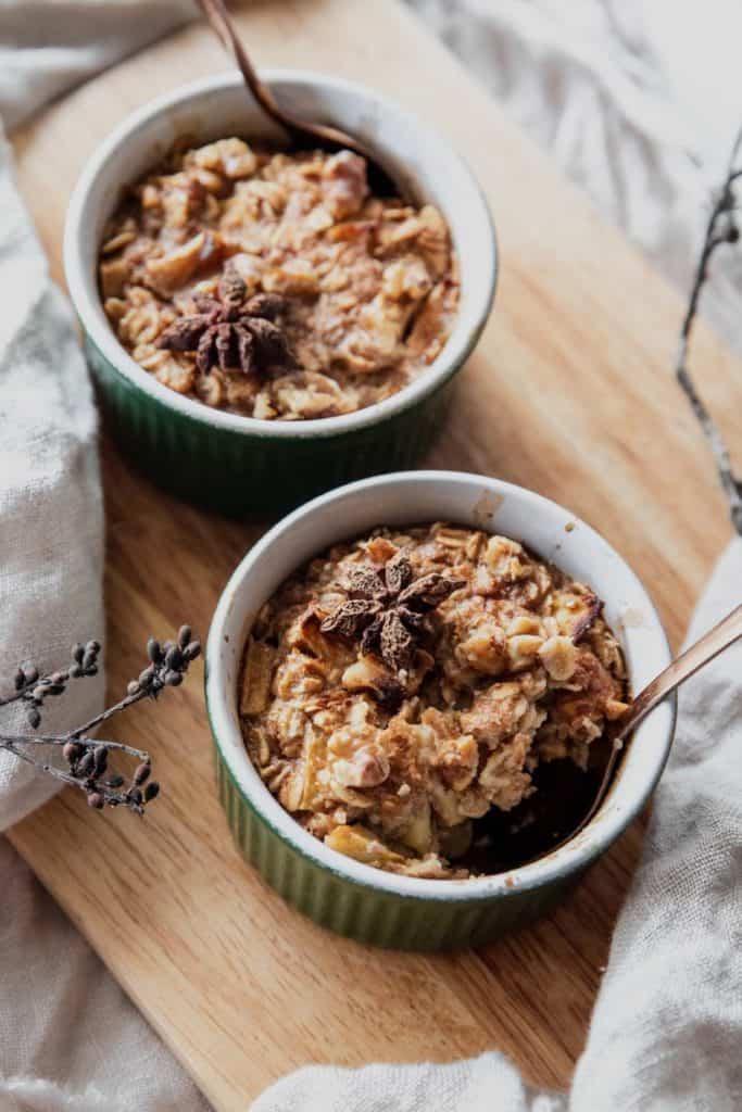 Cooked Apple Pie Baked Oatmeal on cutting board with spoons on top of them.