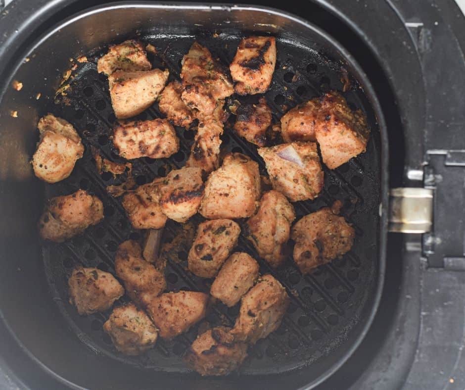 Cooked Chicken Tikka in the air fryer basket.