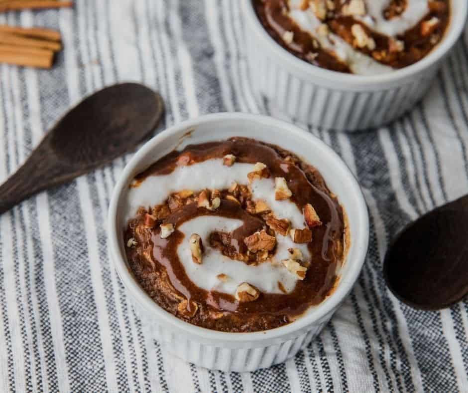 Baked cinnamon roll oatmeal topped with Greek yogurt swirl and cinnamon on a blue and white tablecloth