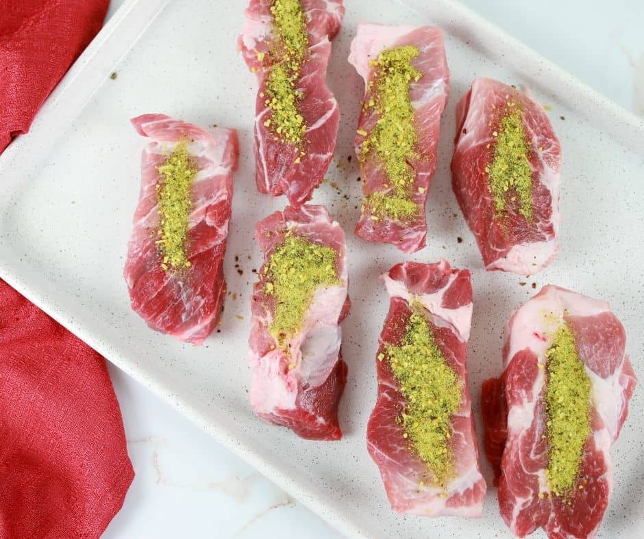 Uncooked ribs with seasoning on them on top of serving plate