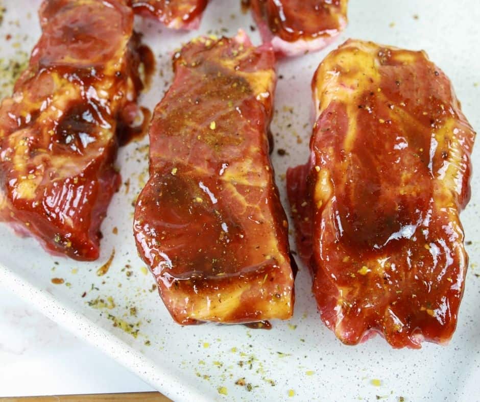 Uncooked ribs with BBQ sauce on them