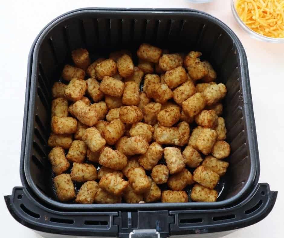 Tater tots arranged in an air fryer basket, cooking at 400°F for 8–10 minutes until golden and crispy, flipped halfway through for even browning.